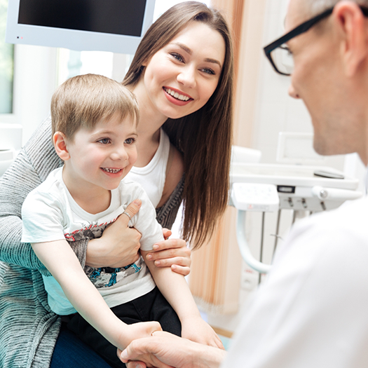 Mother holding child while speaking to dentist
