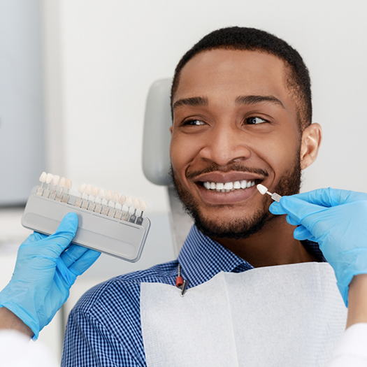 Man in dental chair having teeth shade matched for veneers