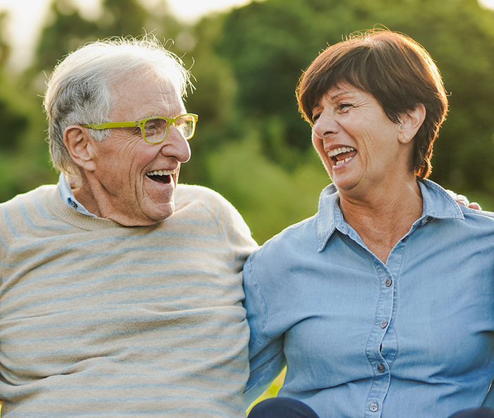 Senior man and woman sitting outside laughing