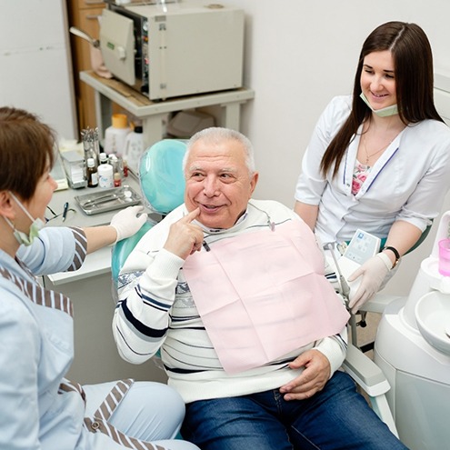 A dentist and dental hygienist talking with an older patient