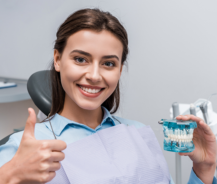 Woman in dental chair giving thumbs up