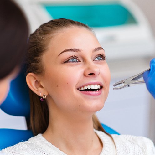 Young woman in dental chair about to have tooth removed with forceps