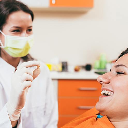 Dentist showing extracted tooth to smiling patient