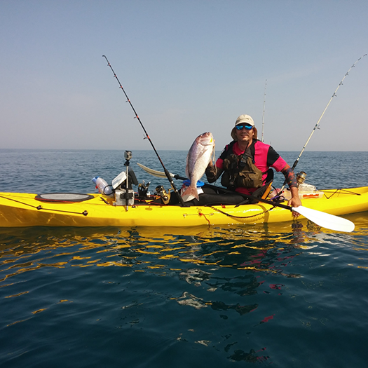 Fisherman in a yellow boat holding a fish