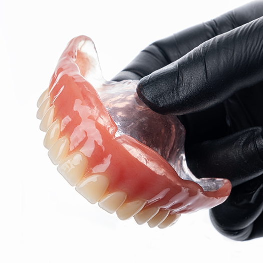 Gloved hand holding full dentures