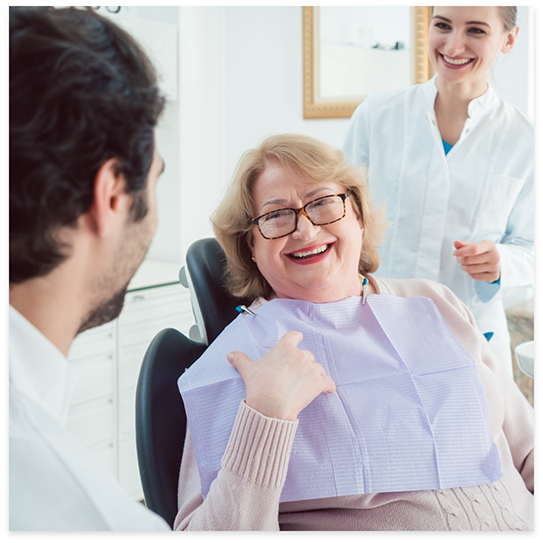 Woman in dental chair smiling and talking to dentists