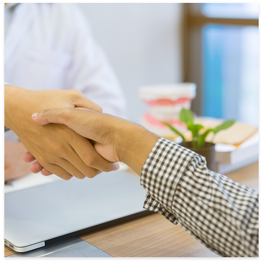 Dentist and patient shaking hands over desk