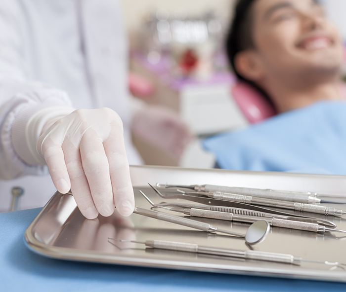 Dentist picking up dental instruments while talking to patient