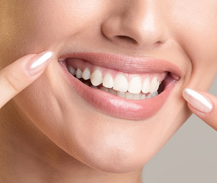 Close-up of woman pointing to her smile