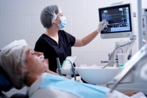 Dentist looking at screen while patient is under sedation.