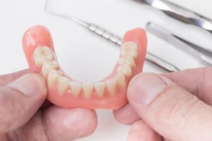 Close-up of fingers holding upper dentures.